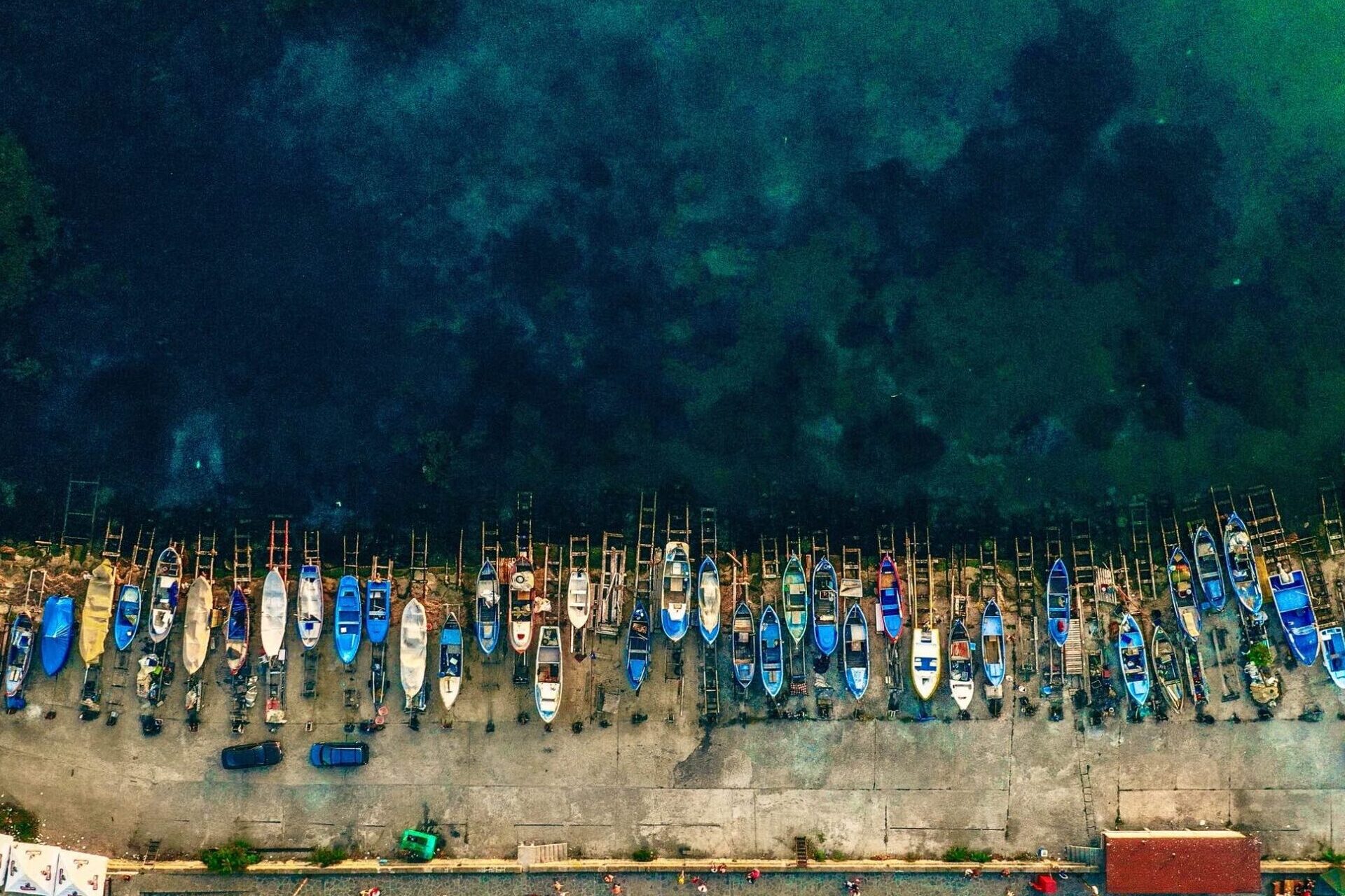 vertical-aerial-shot-different-boats-parked-edge-shore-near-water-2